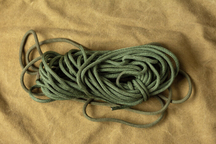 Skein of green nylon paracord rope on army cloth. Bushcraft and wildlife survival items