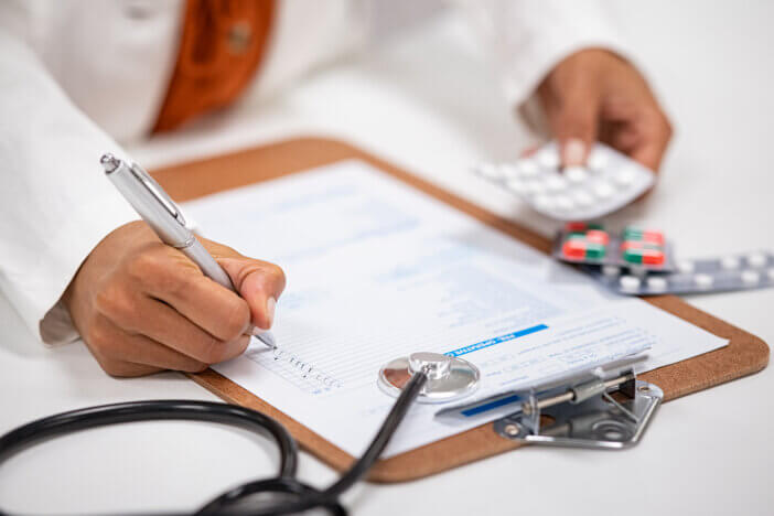 Closeup of woman hands writing medicine inventory. Close up hands of female doctor writing the medicines to be taken on the preoperative model sheet. Pharmacist checking inventory at hospital pharmacy.