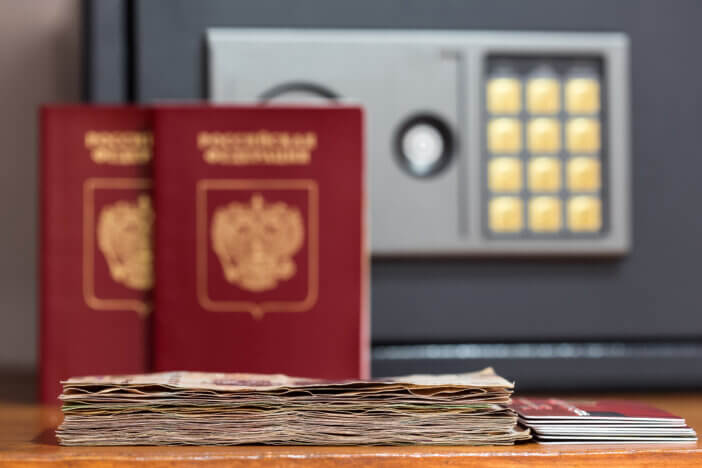 Closeup on banknotes and credit cards in front of safety box and passports. Focus on money and cards