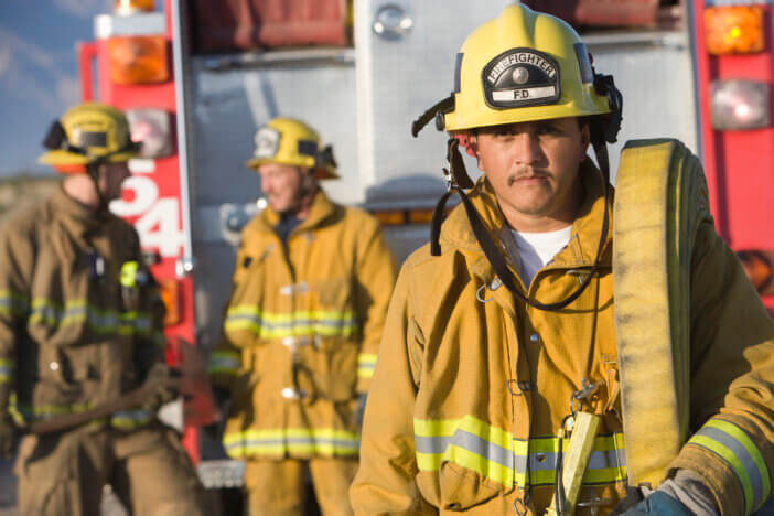 Portrait of firefighter carrying hose