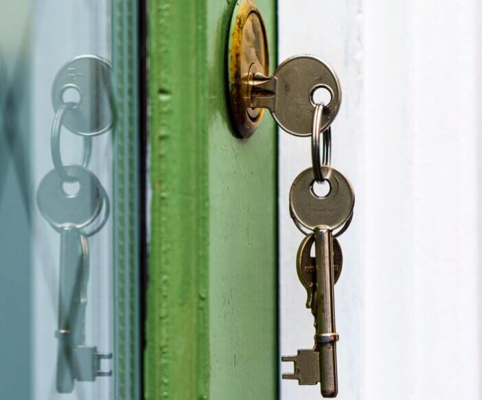 house keys in yale lock in wooden door of house