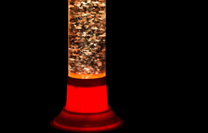 Glitter lava lamp on black background. Genuine vintage 1970 edition, red orange.