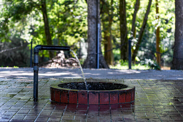 Prattville, Alabama, USA-June 16:2023: Flowing water in the Doster Road Artesian Well House, a public well where people can get water.