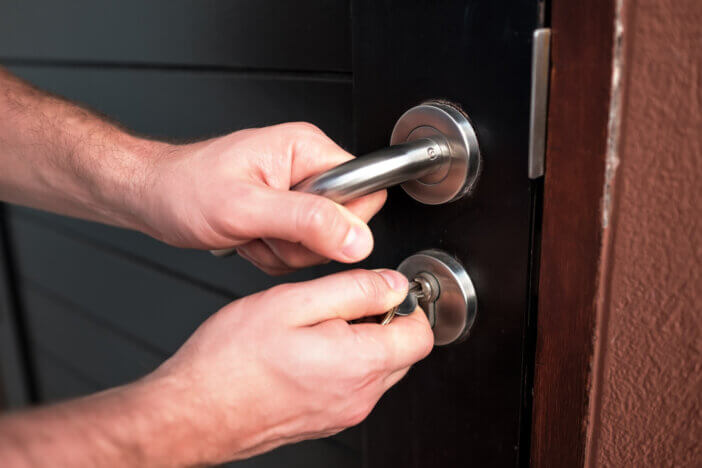 Man hand opening black door with key close up