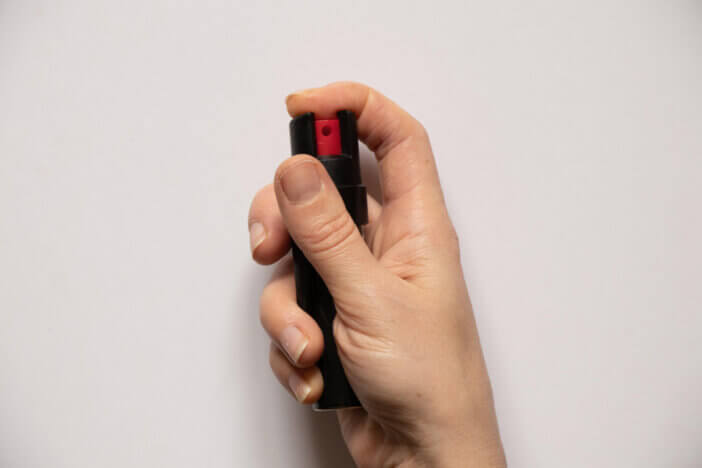 a gas canister in the hands of a girl on a white background, protection from attack