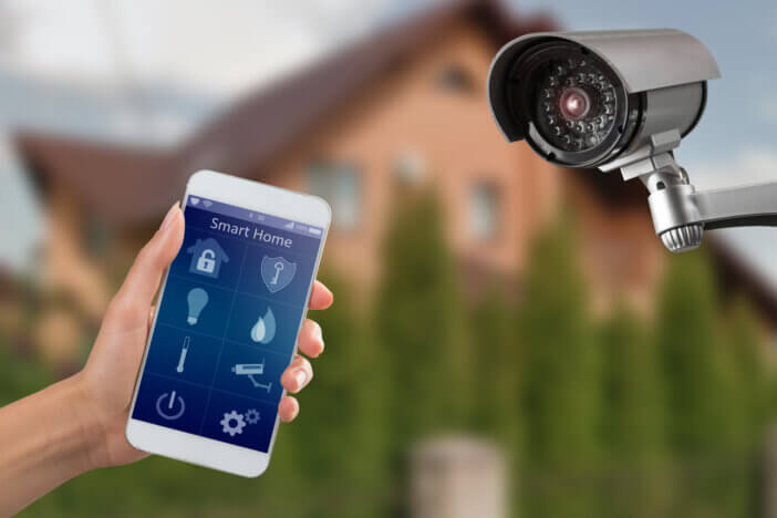 Smartphone with home security app in a hand on the building background