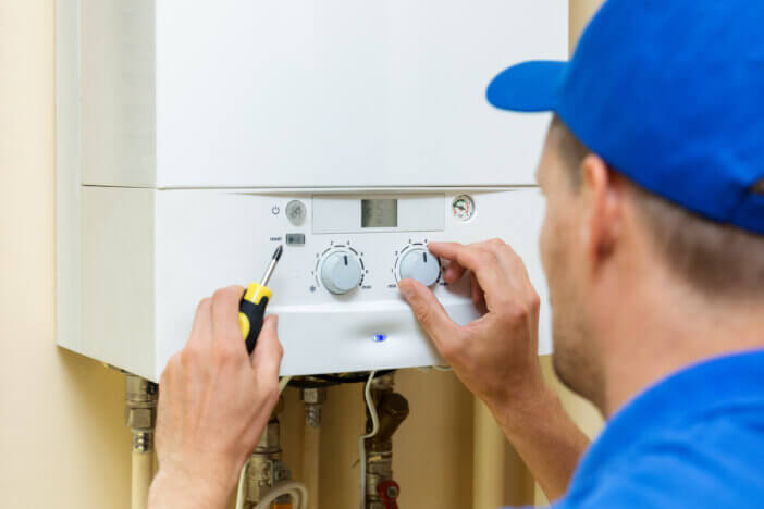 worker set up central gas heating boiler at home
