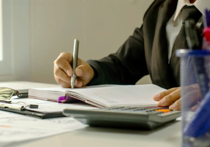 Close-up of a business man taking notes on accounting reports, ideas for costing and saving money.