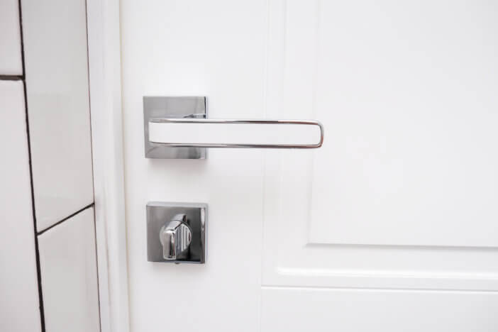White wooden door with a chrome handle and safety security knob for privacy protection.