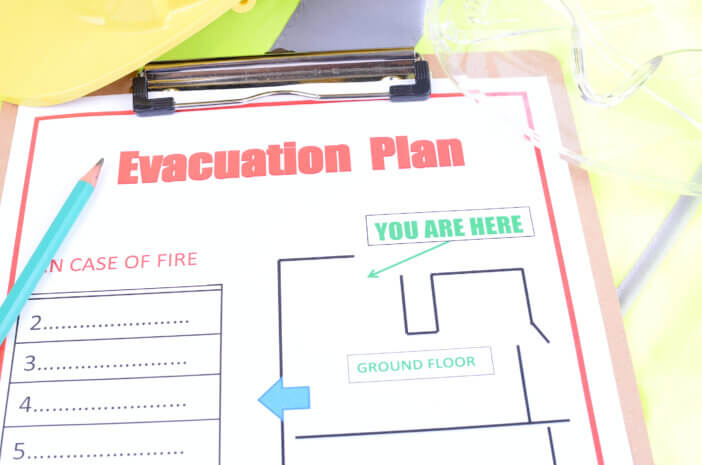 An evacuation plan with a pencil,safety glasses, hard hat and high visibility vest.