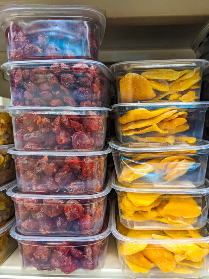 Dried fruits in the store - freeze-dried cherries and mangoes in plastic containers.