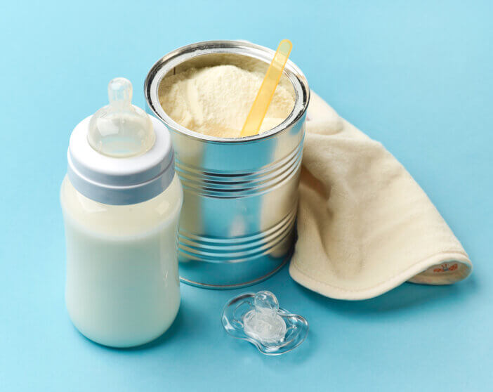 baby milk bottle and powdered milk on blue background