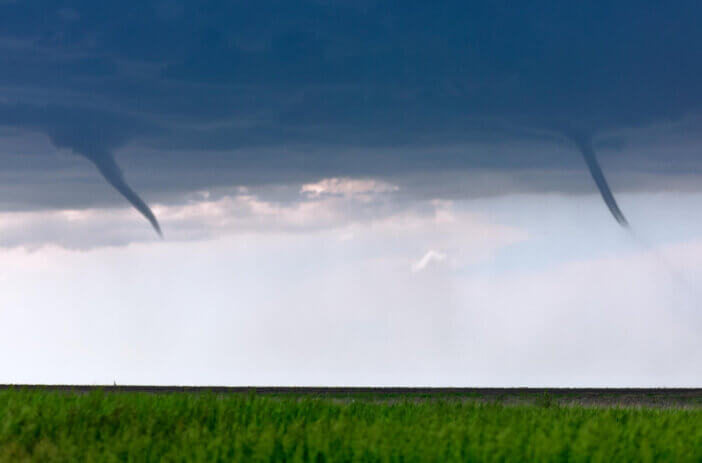 Twin funnels clouds from a pair of landspout tornadoes beneath a summer storm near St. Francis, Kansas.