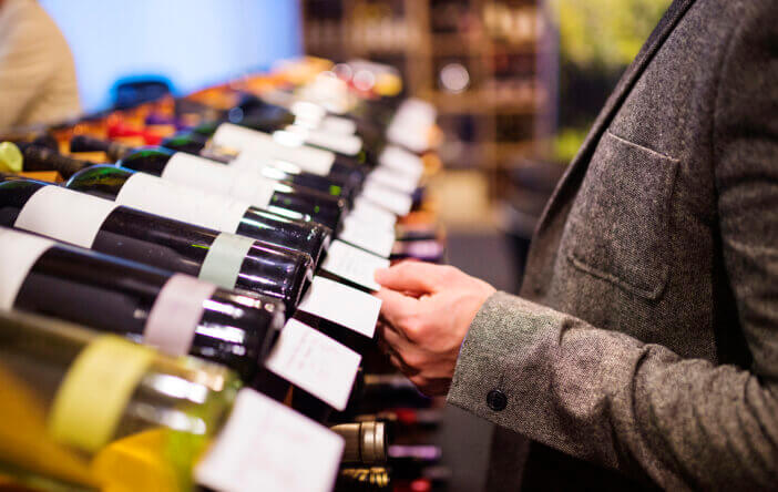Unrecognizable young man in a wine shop choosing a wine