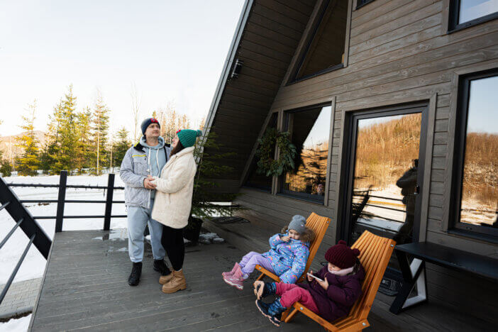 Family with two daughters on terrace off grid tiny house in the mountains.