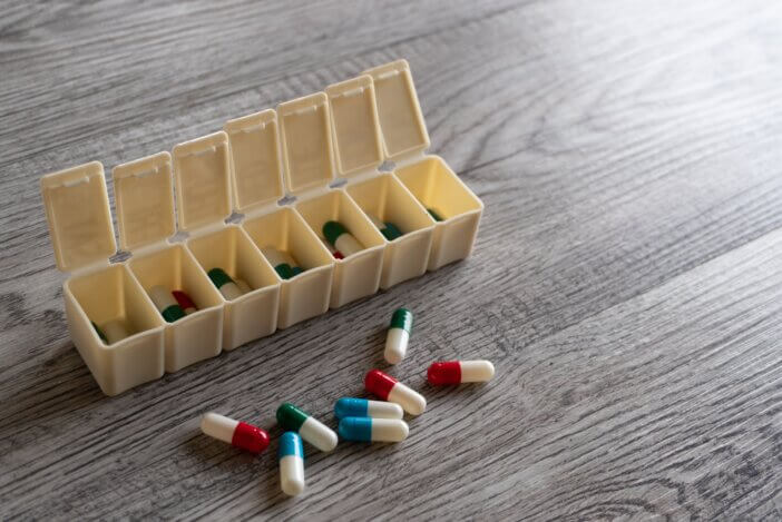 Closeup image of colorful medicine pills and pillbox organizer on table with copy space for text