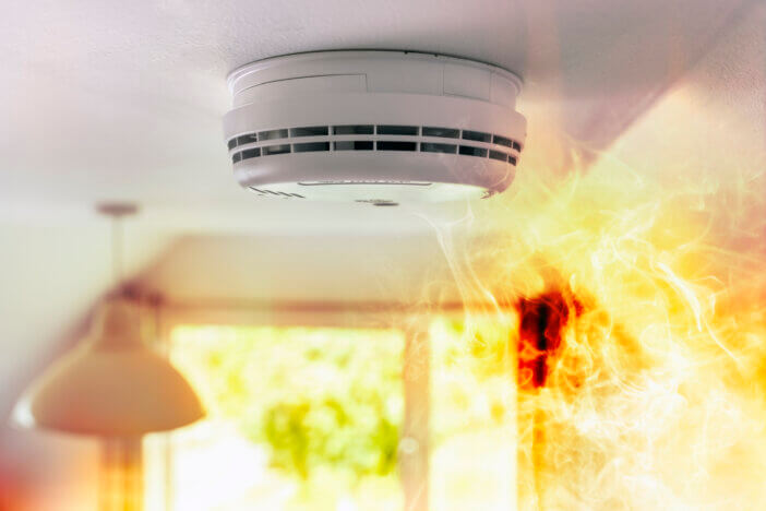 Smoke detector and interlinked fire alarm on ceiling in action background with copy space