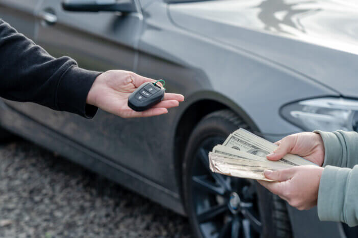 Deal of buying or renting car concept. Hand with the car keys, other hand gives money.