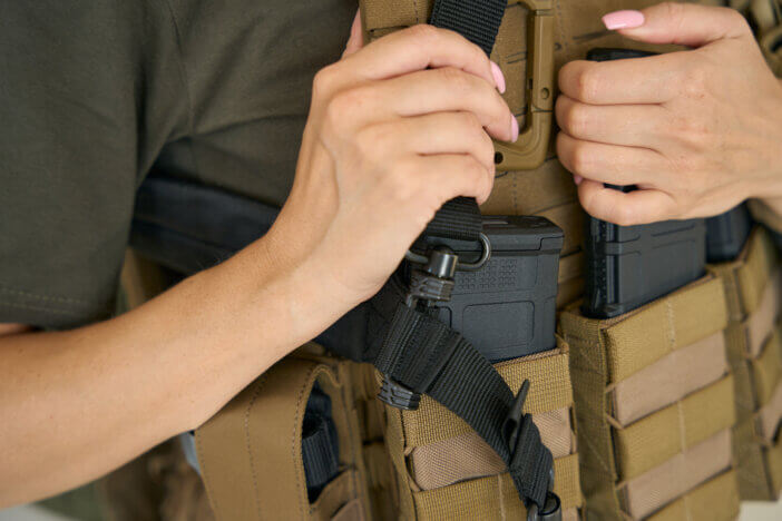 Military woman in a protective body armor, with a holster, pistol and ammunition