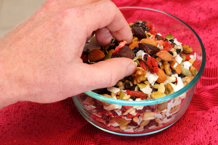 Healthy vegan trail mix of dry fruits and nuts of strawberry, blueberry, black currants, dates, pumpkin seeds, pine nuts, almonds, coconut, walnuts, pistachio, raisins, sesame seeds, and pine nuts..