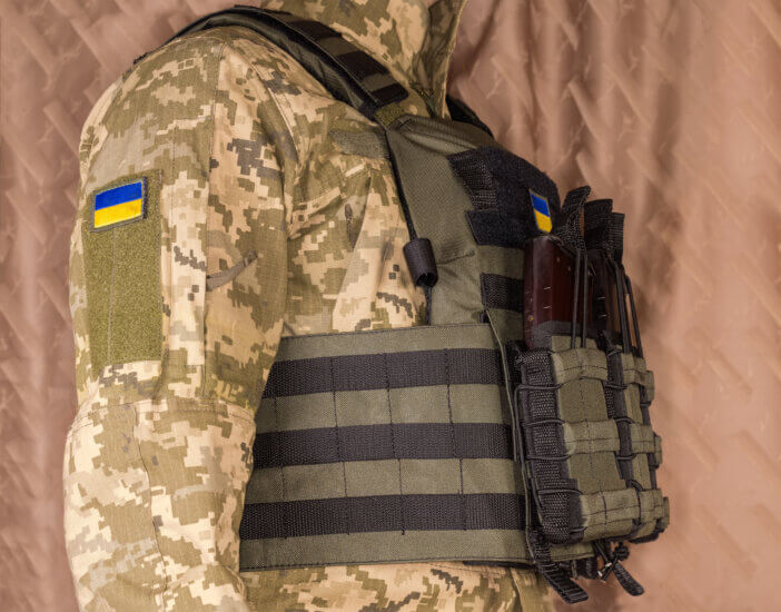 Military bulletproof vest with strapped in tactical pouches of cartridge rifle magazines wear by an Ukrainian soldier, side view
