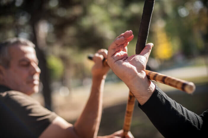 Escrima and kapap instructor demonstrates sticks fighting techniques and training methods in public park. Filipino Martial Arts. Eskrima. Kali