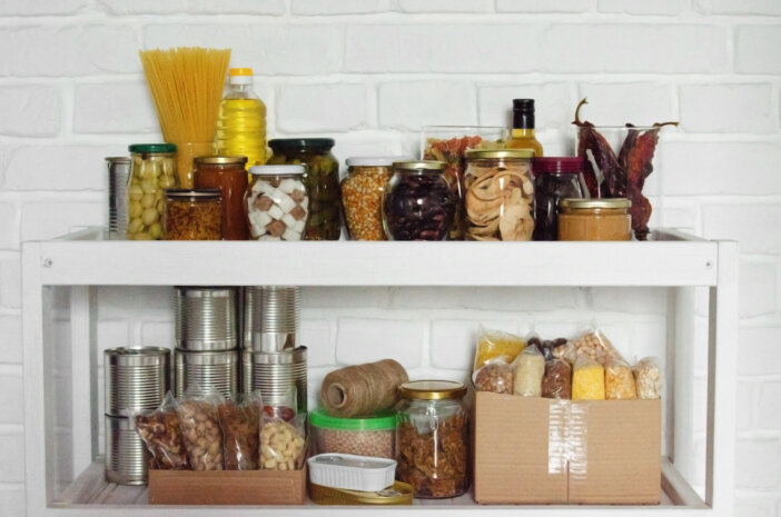 Set of long storage term foods on pantry shelf prepared for disaster emergency conditions on brick wall background