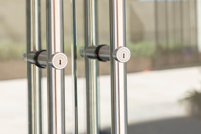 Modern glass door with brushed aluminum handles and lock.