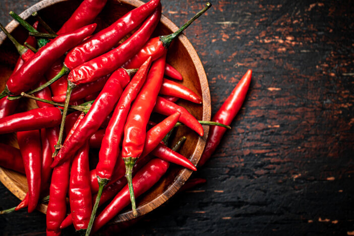 Wooden plate with hot chili peppers. On a rustic dark background. High quality photo