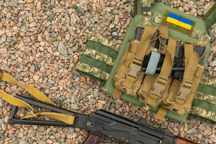 A soldier in a camouflage tactical uniform and a military body armor on a brown background. Bulletproof vest with combat stocks. Ukrainian army. Military concept. No war.