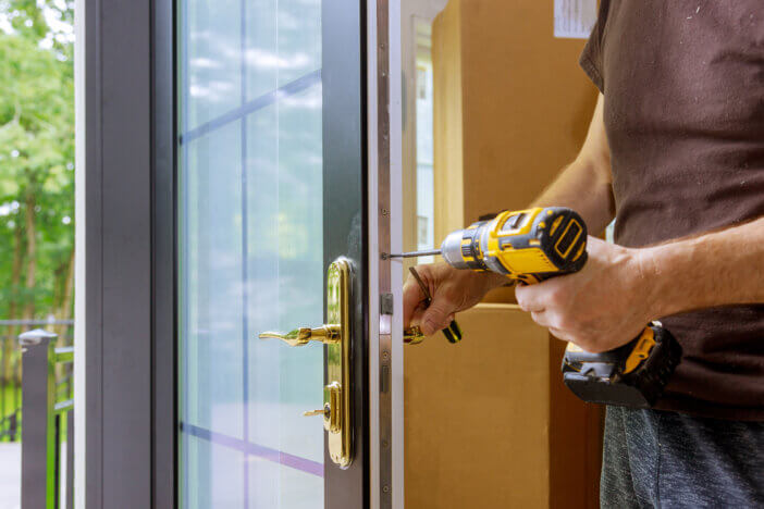 Install the door handle with a lock, Carpenter tighten the screw, using an electric drill screwdriver, close-up.