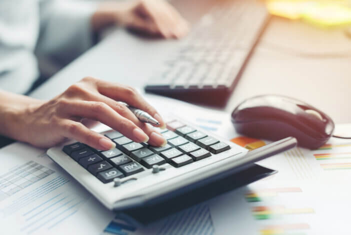 Close up hand of business woman accountant or banker making calculations. Savings, finances and economy audit debt concept