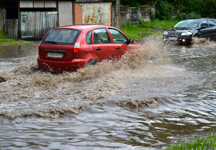 Car rides in heavy rain on a flooded road