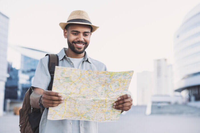 Cheerful man holding map, travel and tourism concept