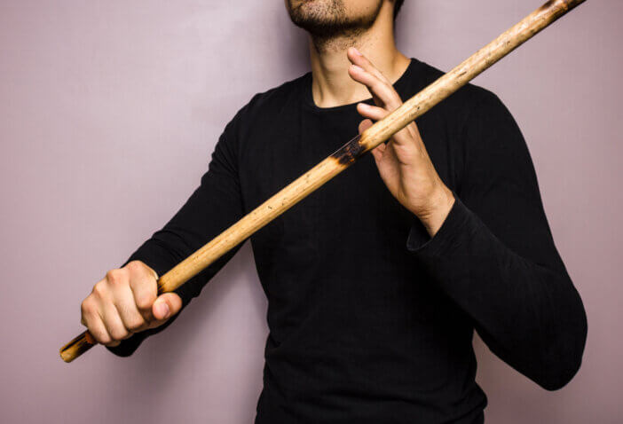 Young practinioner of the Fillipino martial arts eskrima is holding a rattan stick