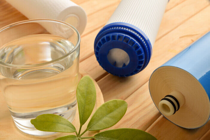 Glass of purified water with domestic environmentally friendly filters on wooden table. Elevated view. Horizontal composition.
