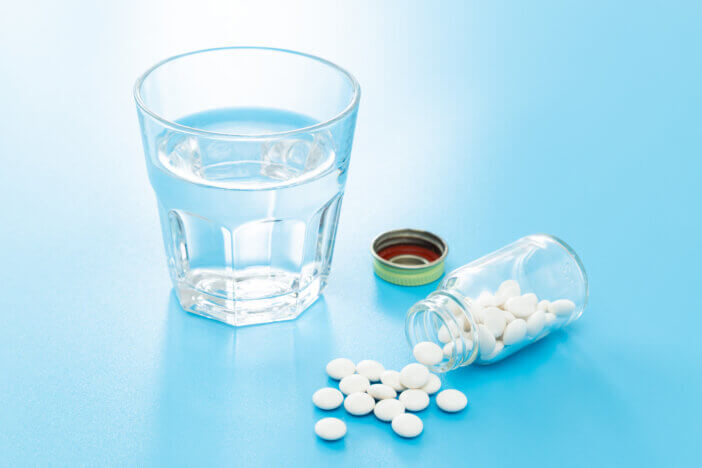 Pills and water on a blue background.