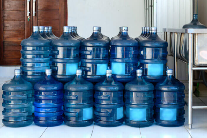 Row of large bottles of drinking water for the cooler. Water delivery. Packed and ready to be sent to customers.