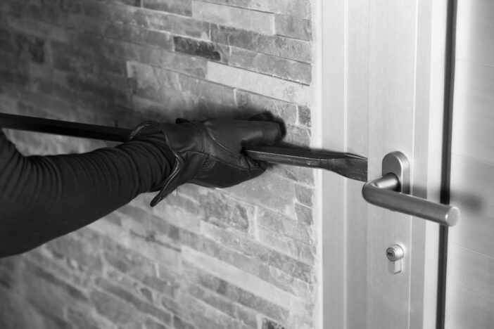 Thief with a bar of iron in the hand to open a door